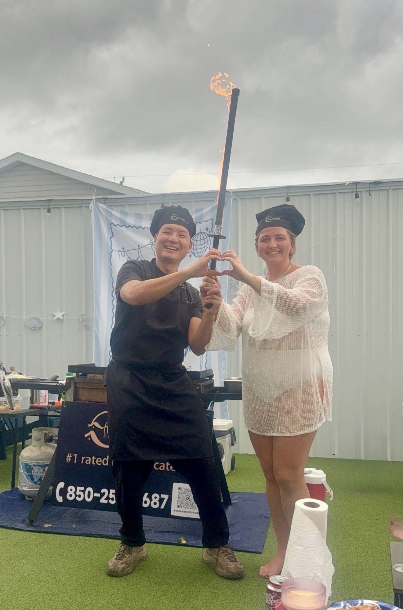 Guest and partner posing with a flaming hibachi sword in a heart shape at a party