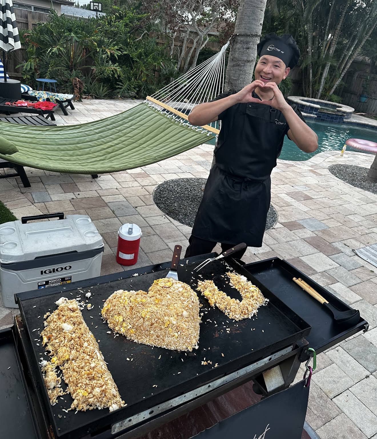 Chef making a heart sign beside a pool with fried rice shaped as I heart U in Florida